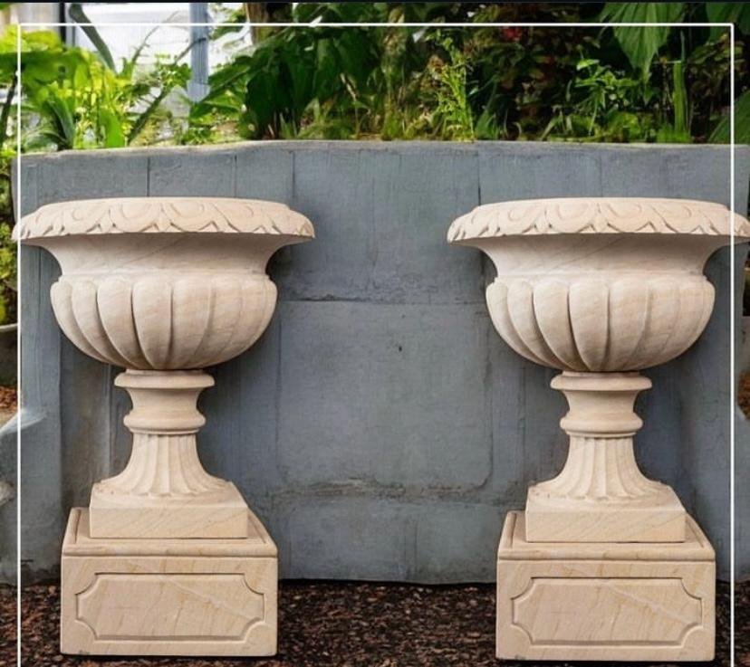 Carved sandstone garden urns on plinths